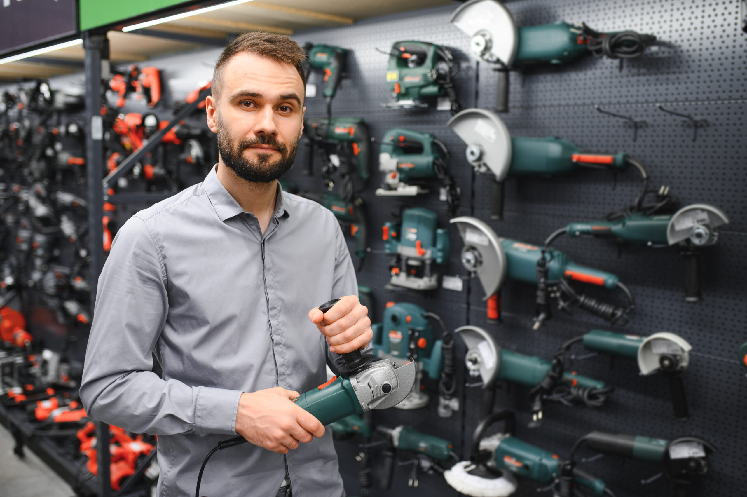 a buyer in a hardware store walks between with a power tool.