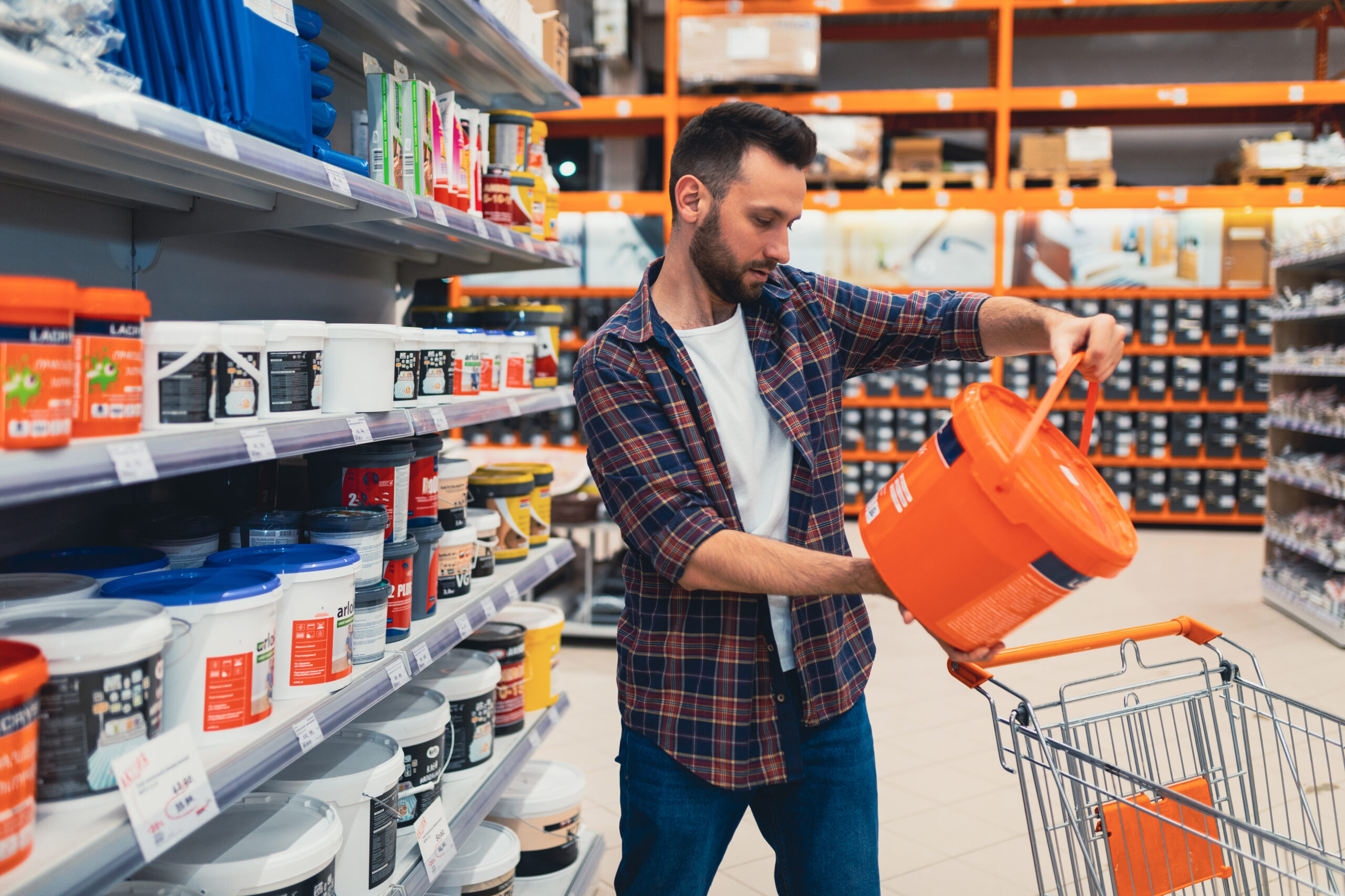 a man in a hardware store chooses paint for construction work.